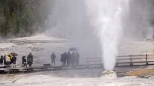 People standing in the cool spray from Beehive Geyser.